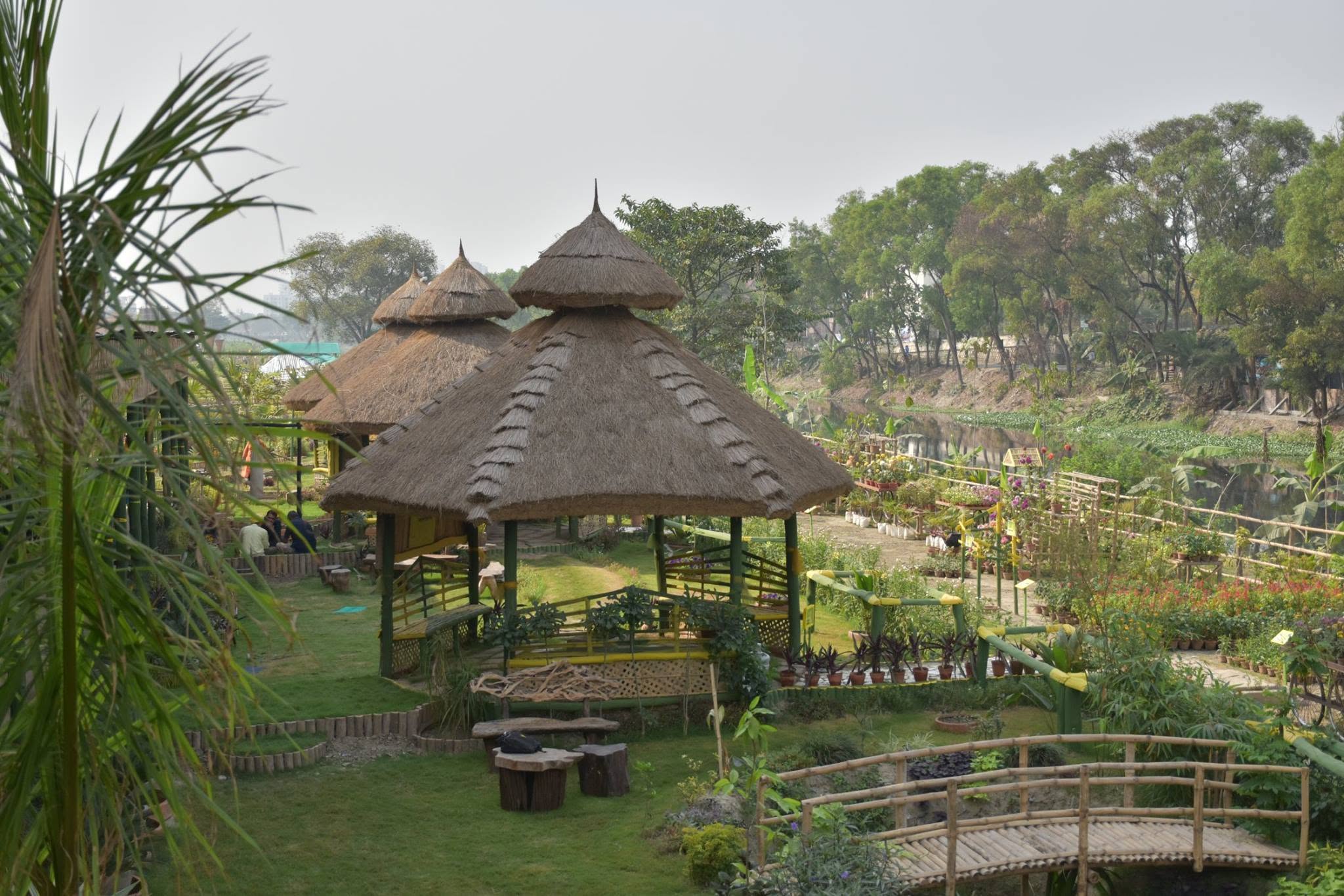 Thatched gazebos, bamboo bridge and gardens beside the canal