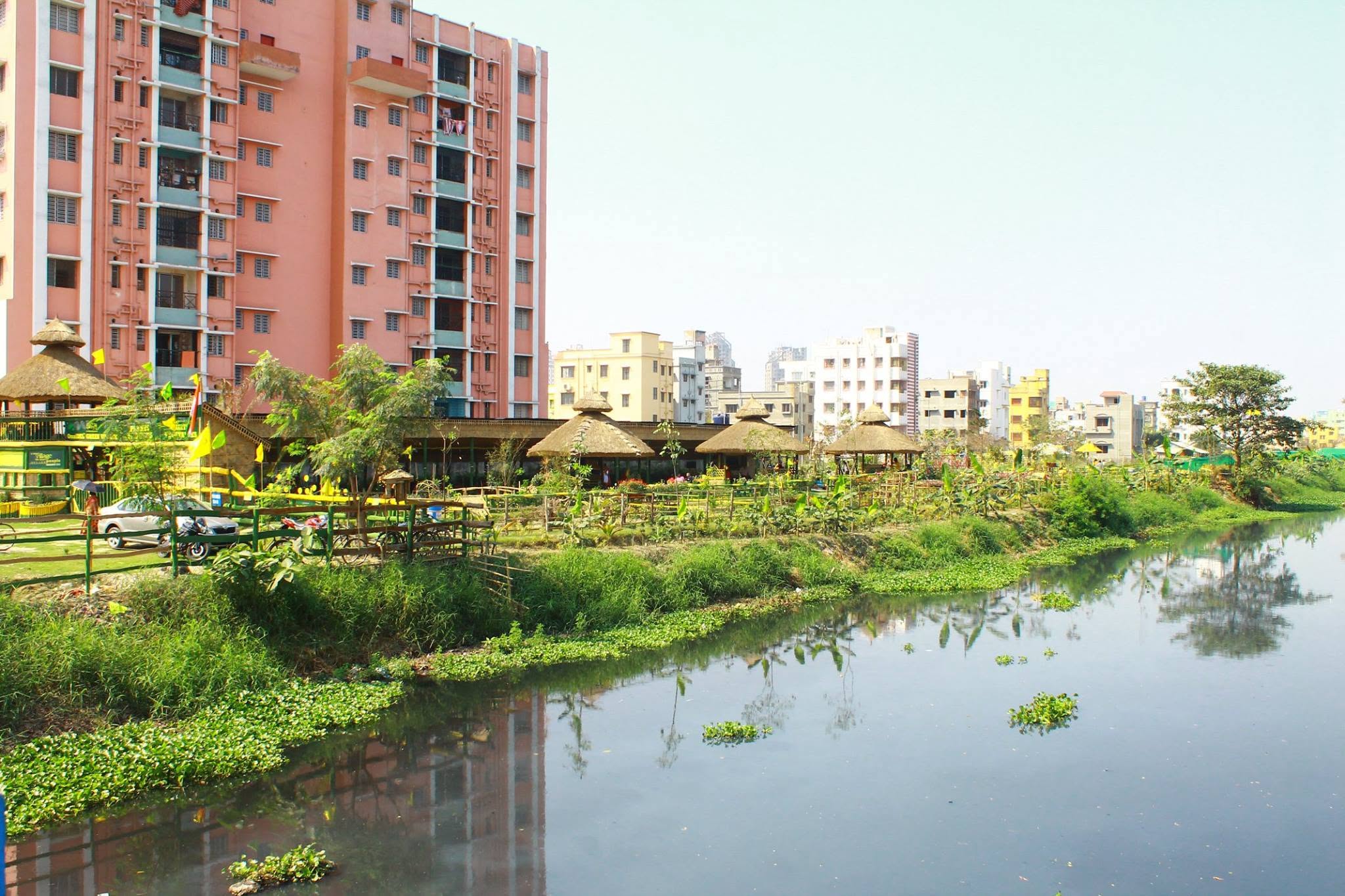 The green village on the canal bank against New Town apartment towers