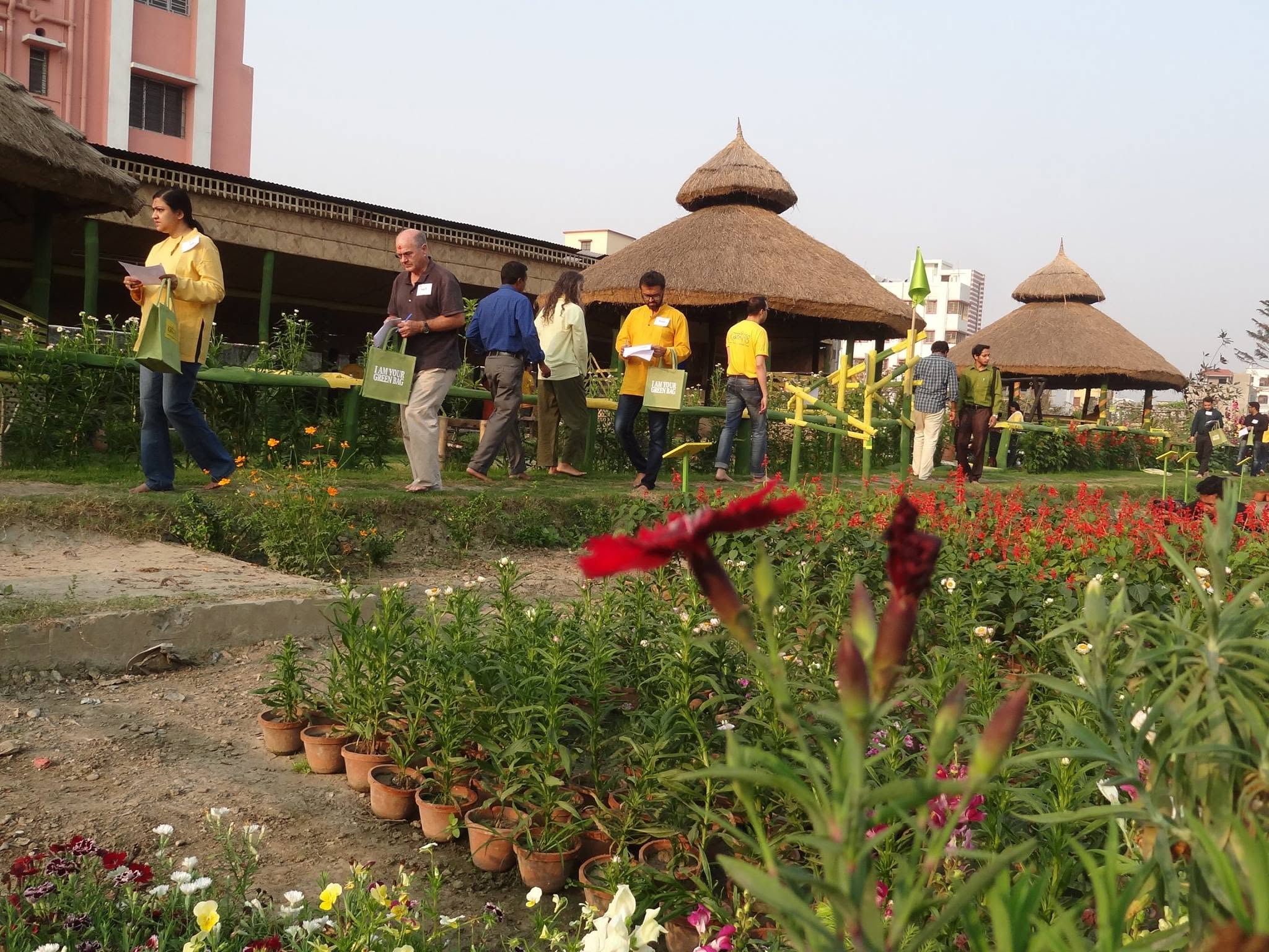 Visitors with green cloth bags walking through flower beds